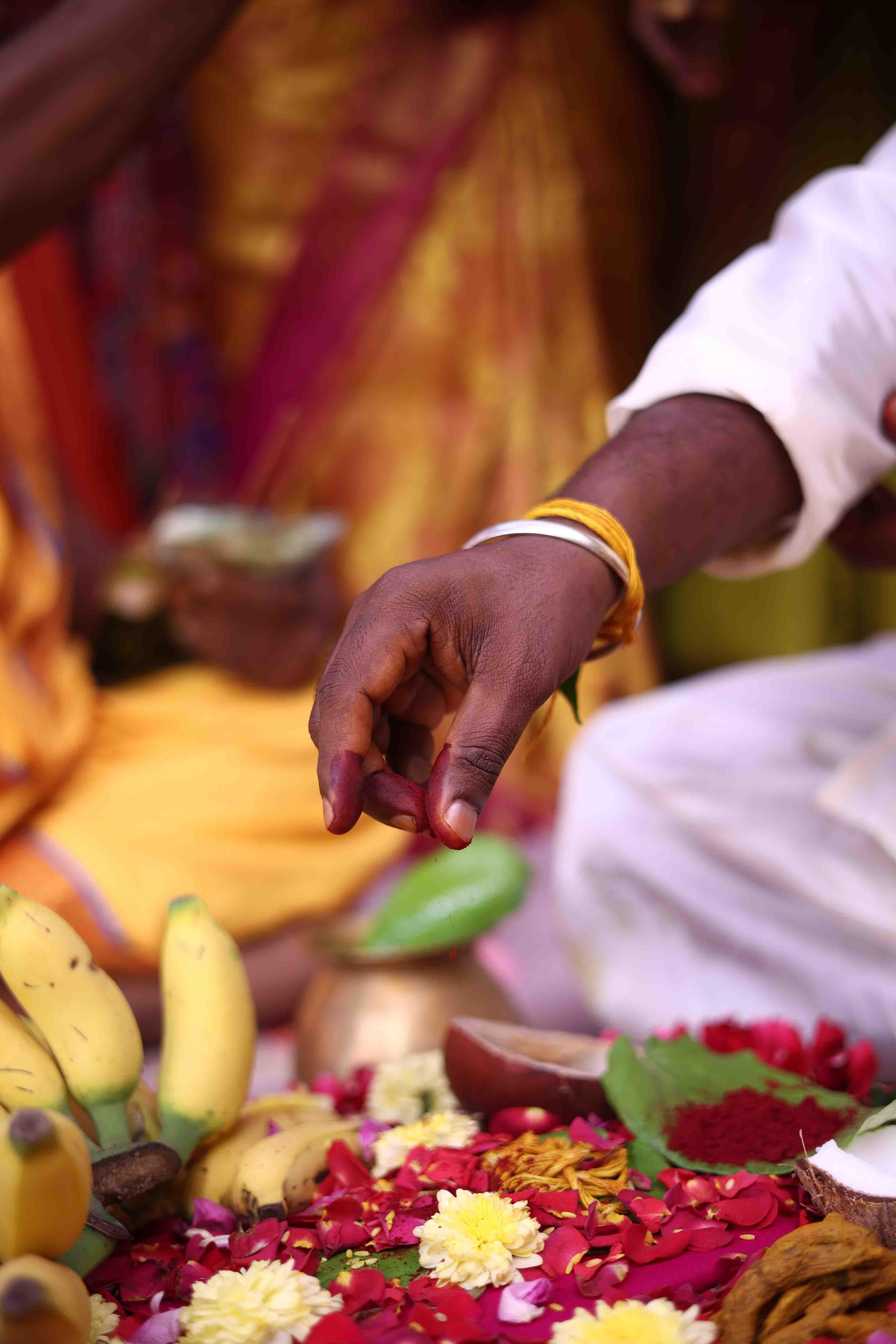 Hands performing sacred vow rituals with flowers and offerings
